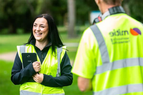 Two Mitie colleagues smiling and wearing high vis vests